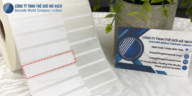 Ưu điểm của tem trang sức 56x12mm đuôi 40mm Tem trang sức nhựa PVC 56x12mm đuôi 40mm giải quyết bài toán định danh sản phẩm kim hoàn nhờ sự kết hợp giữa thiết kế thông minh, diện tích in tối ưu và vật liệu kháng nhiệt bền bỉ. 1. Đuôi tem 40mm chuyên dụng cho nhẫn, bông tai, dây chuyền Chiều dài đuôi tem 40mm cung cấp độ rộng linh hoạt để luồn qua các sản phẩm như nhẫn, lắc tay, dây chuyền hoặc bông tai mà không gây vướng víu. Cơ chế kẹp đuôi vào giữa hai mặt thân gập giúp cố định tem nhãn ổn định mà không cần dán trực tiếp lên bề mặt vàng bạc. Thiết kế này giúp loại bỏ nguy cơ để lại cặn keo bẩn trên trang sức khi khách hàng thử đồ. 2. Không gian in ấn tối ưu từ thân tem 28x12mmx2 Kích thước thân sau khi gập đôi đạt 28x12mm, tạo ra hai mặt hiển thị song song giúp chủ tiệm vàng dễ dàng sắp xếp bố cục nội dung. Bề mặt này cung cấp không gian vừa đủ để in mã vạch QR, logo thương hiệu, cùng các thông số kỹ thuật như trọng lượng, tiền công và hàm lượng vàng, giúp khách hàng tra cứu thông tin minh bạch. 3. Chất liệu PVC bền bỉ dưới đèn tủ trưng bày và tần suất thử liên tục Decal nhựa PVC sở hữu khả năng chịu nhiệt độ tốt, giúp tem không bị giòn, ố vàng hay quăn mép khi phơi sáng liên tục dưới đèn LED/Halogen của tủ kính trưng bày. Đặc tính vật lý dẻo dai, xé không rách giúp tem nguyên vẹn, không bị đứt gãy khi nhân viên kiểm kho hoặc khi khách hàng liên tục cầm nắm, đeo thử trang sức. Mua tem trang sức 56x12mm đuôi 40mm chất lượng tại Thế Giới Mã Vạch Thế Giới Mã Vạch là đơn vị trực tiếp gia công các dòng tem trang sức với cam kết bế cắt chuẩn xác kích thước 56x12mm đuôi 40mm, đảm bảo tính thẩm mỹ cao khi gắn lên phom nhẫn hay vòng tay. Về mặt kỹ thuật, đội ngũ chuyên viên sẽ tư vấn vật tư đồng bộ, khuyên dùng cuộn mực in có khổ rộng lớn hơn tổng chiều ngang cuộn tem (ví dụ mực khổ 60mm hoặc 110mm) nhằm bảo vệ đầu in máy Desktop khỏi tình trạng ma sát trực tiếp với mép giấy. Ngoài kích thước tiêu chuẩn, Thế Giới Mã Vạch còn hỗ trợ nhận bế kích thước theo yêu cầu riêng và cung cấp dịch vụ khử keo phần đuôi với chính sách giá sỉ cạnh tranh. Tem trang sức 56x12mm đuôi 40mm diện tích hiển thị lớn